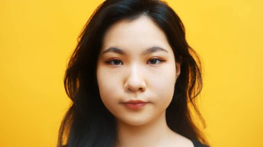 Sarı arka planda izole edilmiş genç Asyalı kadın portresi.