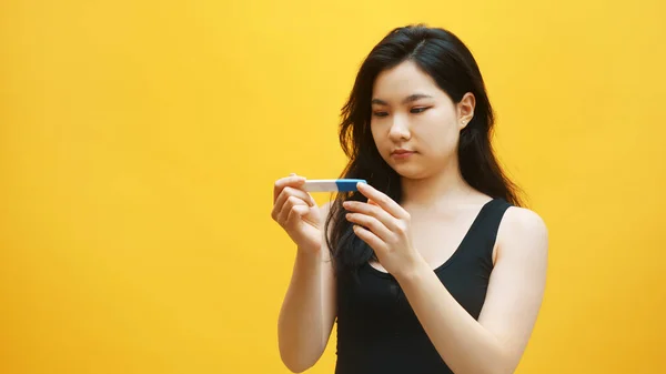 Impaciente jovem mulher asiática olhando para o teste de gravidez à espera de resultados. Planeamento familiar e conceito de gravidez indesejada — Fotografia de Stock