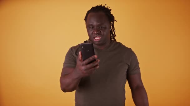 Homem negro afro-americano chocado lendo uma mensagem de texto no smartphone — Vídeo de Stock