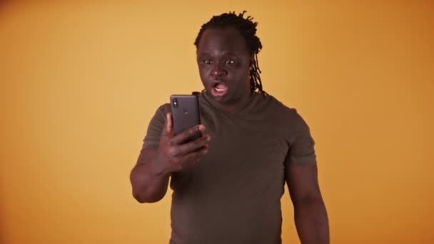 Šokovaný africký černoch, který čte textovou zprávu na smartphonu — Stock video