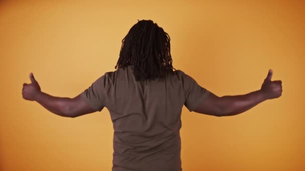 Vista posteriore di afro americano nero uomo con i pollici in su isolato su sfondo arancione — Video Stock