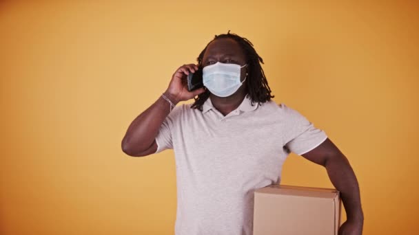 Repartidor africano con máscara facial - mensajero entregando la caja del paquete - espacio de copia aislado — Vídeos de Stock