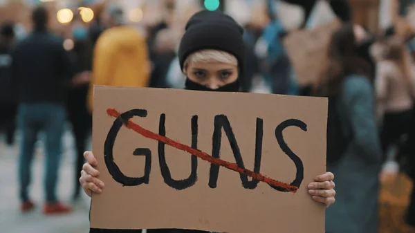 Nincs fegyver. Egy fiatal nő arcmaszkkal, aki zászlót tart a fegyveres erőszak ellen. Demonstráció és forradalom koncepciója — Stock Fotó
