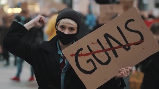 Sin armas. Mujer joven con máscara facial sosteniendo pancarta contra la violencia armada. Concepto de demostración y revolución — Vídeo de stock