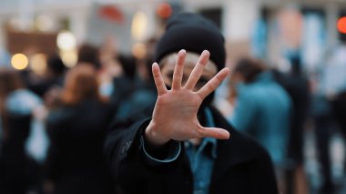 Kes şunu! Yüzü maskeli genç bir kadın kamerayı durduruyor ve elini uzatıyor. Gösteri ve protesto