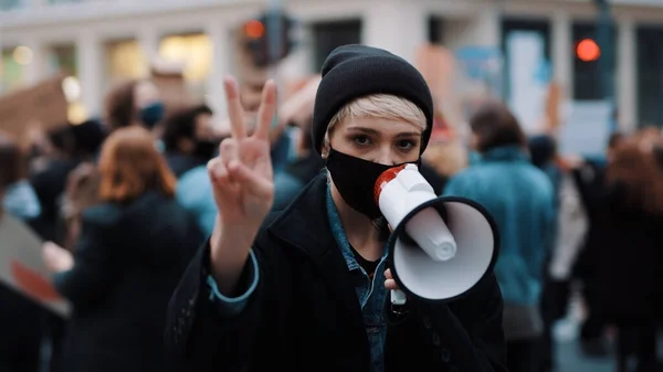 Mulher com máscara facial e megafone apoiando protestos anti-racismo. gesto de paz — Fotografia de Stock