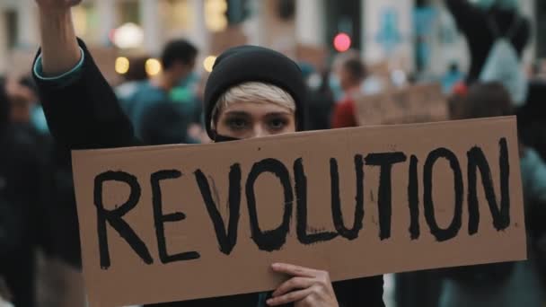 Concepto de Revoultion. Mujer joven infeliz con máscara facial y pancarta protestando en la multitud — Vídeos de Stock