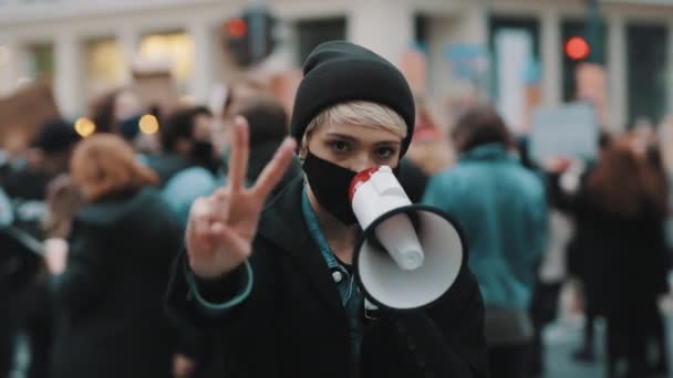 Vrouw met gezichtsmasker en megafoon ter ondersteuning van anti-racisme protesten. Vredesgebaar — Stockvideo