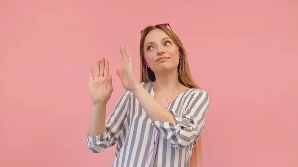 Young caucasian woman with pink sunglasses listening to the music and dancing. Isolated on the pink background — Stock Photo, Image