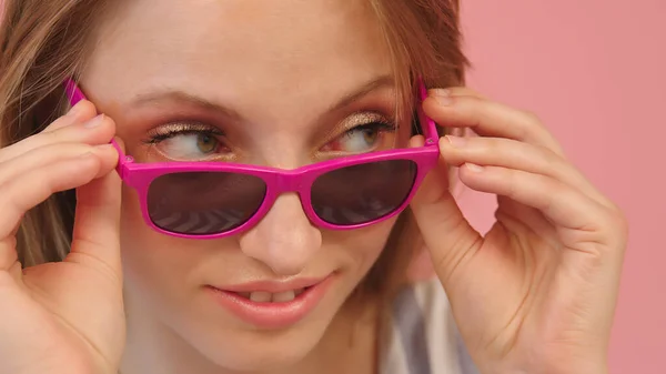 Retrato de jovem caucasiana olhando sobre os óculos de sol rosa — Fotografia de Stock