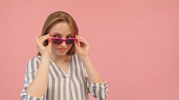 Junge kaukasische Blondine blickt über die rosa Sonnenbrille. Kopierraum — Stockfoto