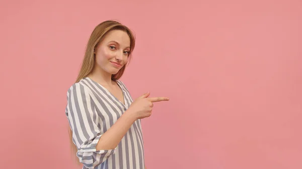 Jovem confiante com camisa listrada apontando para o espaço vazio, fundo rosa — Fotografia de Stock