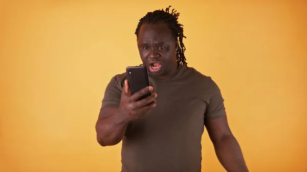 Šokovaný černoch z Afriky se dívá na obrazovku svého telefonu. Neočekávaná textová zpráva nebo špatná zpráva — Stock fotografie