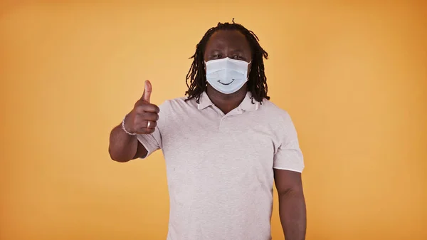 Afro americano negro hombre con sonriente mascarilla mostrando pulgar hacia arriba — Foto de Stock