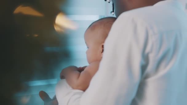 Father and son enjoying holiday at home. Newborn baby and daddy looking through the window — Αρχείο Βίντεο