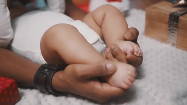 Da vicino, papà che tiene i piedi del bambino carino circondato da regali di Natale — Video Stock