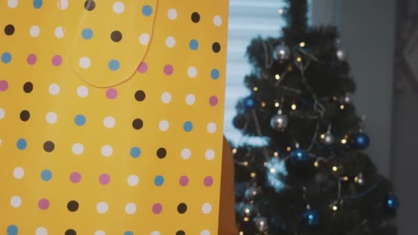 Stagione natalizia. Uomo nero afroamericano con in mano una grande shopping bag dorata un regalo davanti all'albero di Natale — Video Stock