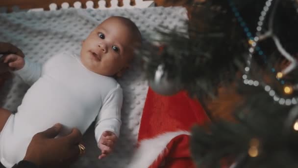 Bebê primeiro Natal. Bebê recém-nascido admirando a decoração da árvore de Natal enquanto brinca com o pai — Vídeo de Stock