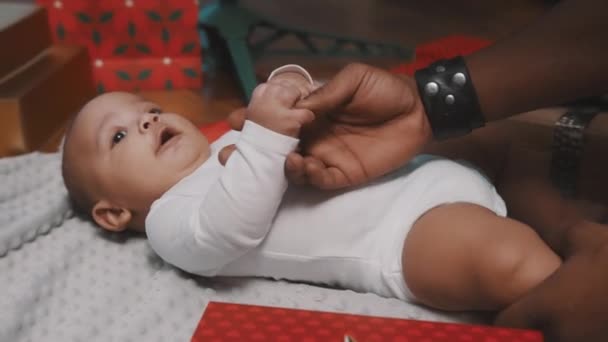 Baby first christmas. Papa und Neugeborenes spielen umgeben kaufen rote Geschenkboxen — Stockvideo