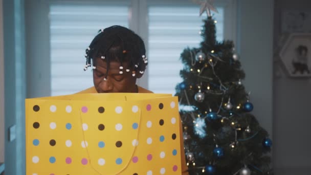 Regalo di Natale. Afroamericano uomo nero in possesso di grande shopping bag d'oro e guardando il presente all'interno — Video Stock