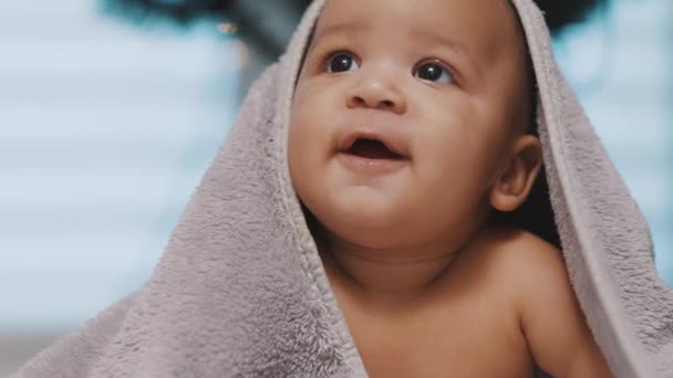 Tutup bayi hitam lucu dengan kepala ditutupi dengan handuk halus Pohon Natal di latar belakang — Stok Video