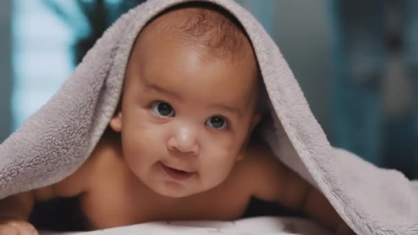 Primer plano de lindo bebé negro con la cabeza cubierta con toalla esponjosa — Vídeos de Stock