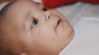 Sevimli koyu tenli bebek havluya uzanıp gülüyor.