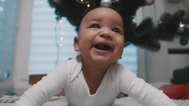 Bebê preto adorável tendo um tempo de barriga sob a árvore de Natal cercada por presentes. Primeiro bebê natal — Vídeo de Stock