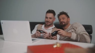 Video oyunu oynayan mutlu eşcinsel çift. Adam kaybederken ortağını itiyor.