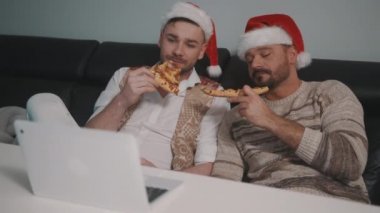 Erkek homoseksüel çift Noel günü pizza yiyor ve film seyrediyor.