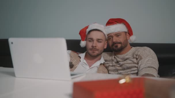Gay mâle couple avec santa claus chapeaux câlins et regarder film triste romantique sur l 'noël veille — Video