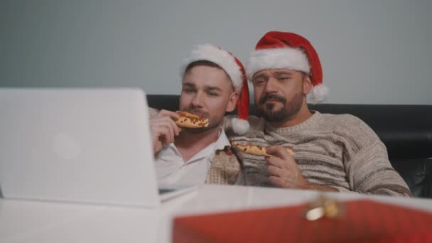 Drôle caucasien gay couple regarder films sur l 'portable sur l' Noël veille et manger pizza — Video