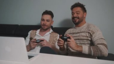 Genç eşcinsel çift oyun oynarken kumandayı kullanıyor. Aynı seks partnerlerinin yaşam tarzı