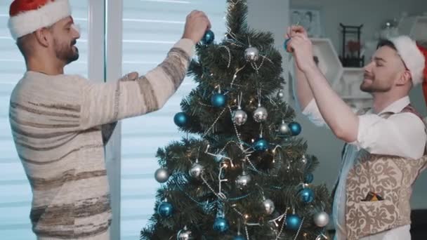 Homosexual pareja masculina decorando árbol de navidad — Vídeo de stock
