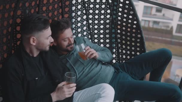 Junge Freunde entspannen sich und trinken Bier auf dem Balkon. Liebe und Zuneigung gleichgeschlechtlicher Partner — Stockvideo