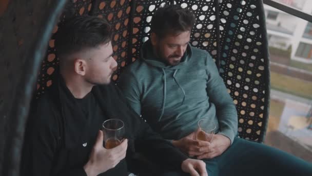 Jovens namorados relaxando e bebendo cerveja na varanda. Amor e afeto dos parceiros do mesmo sexo — Vídeo de Stock