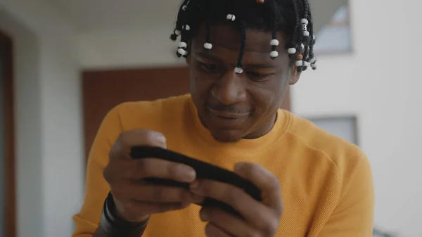 Retrato del hombre negro afroamericano enfocado jugando juegos en el teléfono inteligente — Foto de Stock