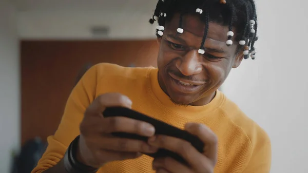 Retrato del hombre negro afroamericano enfocado jugando juegos en el teléfono inteligente — Foto de Stock