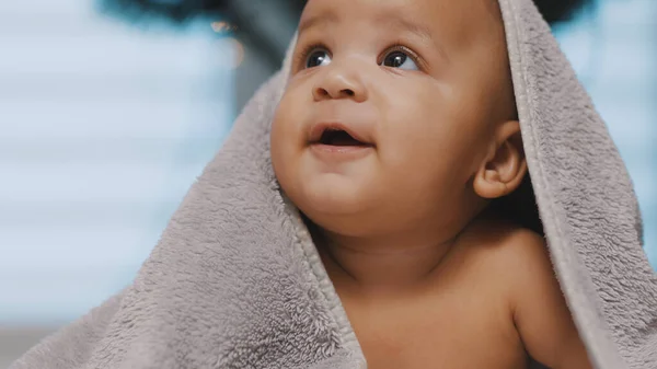 Nahaufnahme von niedlichen schwarzen Baby mit Kopf bedeckt mit flauschigem Handtuch Christmette Baum im Hintergrund — Stockfoto