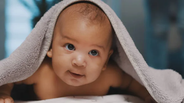 Adorável pele escura bebê coberto com toalha se divertindo barriga tempo — Fotografia de Stock