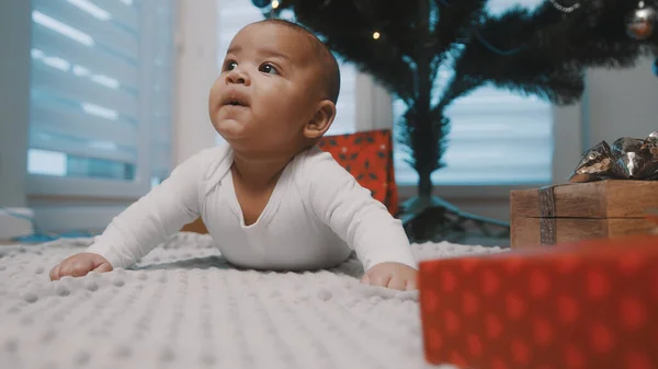 Imádnivaló újszülött, akinek a pocakját ajándékok veszik körül. Első baba karácsony — Stock Fotó