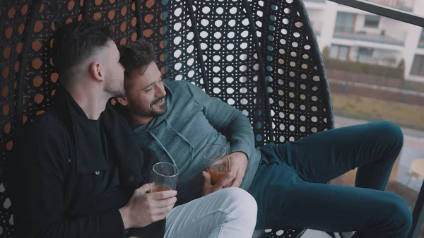 Romântico gay casal relaxante com cerveja no o varanda balanço — Fotografia de Stock
