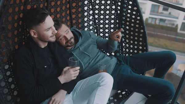 Романтична гей пара розслабляється з пивом на балконі гойдалки — стокове фото