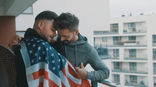 Gelukkig knap gay paar knuffelen onder USA vlag op het balkon — Stockfoto