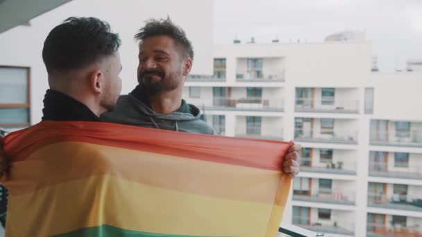 หนุ่มตื่นเต้นคู่ชายเกย์ยืนอยู่บนระเบียงปกคลุมด้วยธงรุ้ง — วีดีโอสต็อก