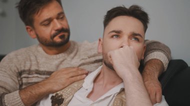 Haberler kötü. Adam neredeyse ağlayan ortağını sakinleştiriyor.