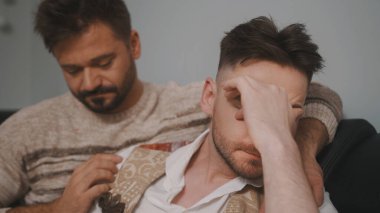 Haberler kötü. Adam neredeyse ağlayan ortağını sakinleştiriyor.