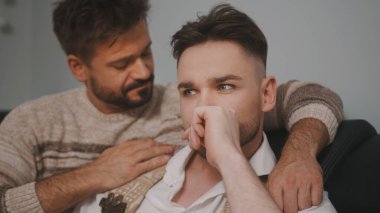 Haberler kötü. Adam neredeyse ağlayan ortağını sakinleştiriyor.