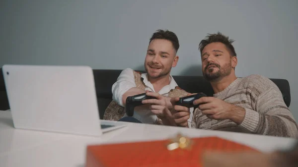 Emocionada pareja gay jugando videojuegos en el portátil usando joystic — Foto de Stock