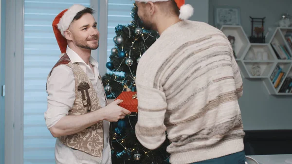 Feliz pareja gay decorando árbol de navidad e intercambiando regalos — Foto de Stock